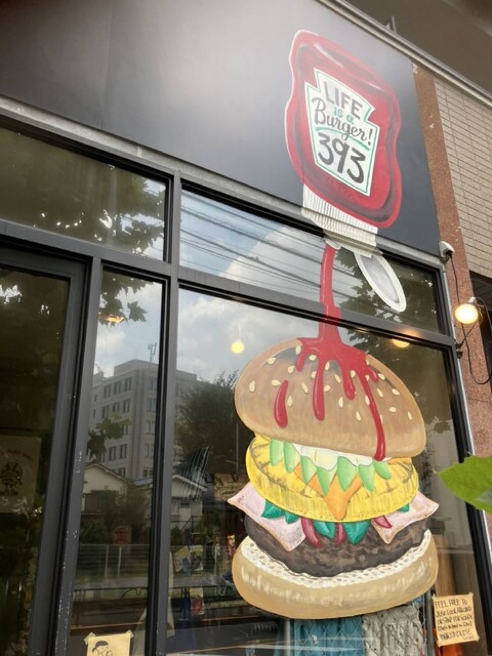 「LIFE IS Burger! 393」と積み重なったバーガーが描かれた窓のウォールアート